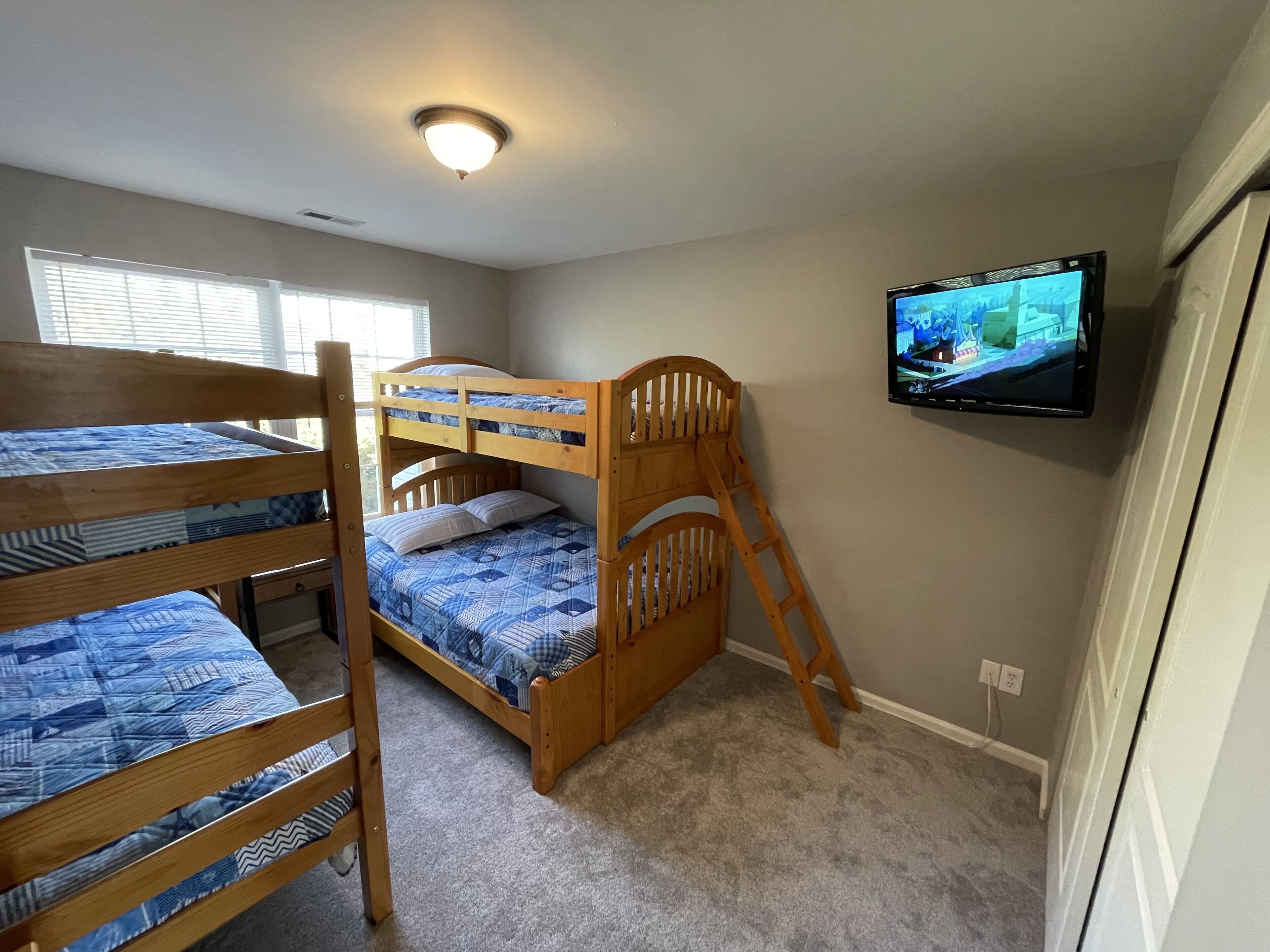 A room with bunk beds, a television, and a ceiling light.