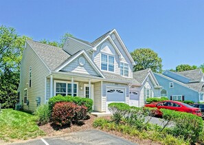 A single-story house with a gabled roof, a front garage, and a well-maintained front yard with shrubs and a lawn.