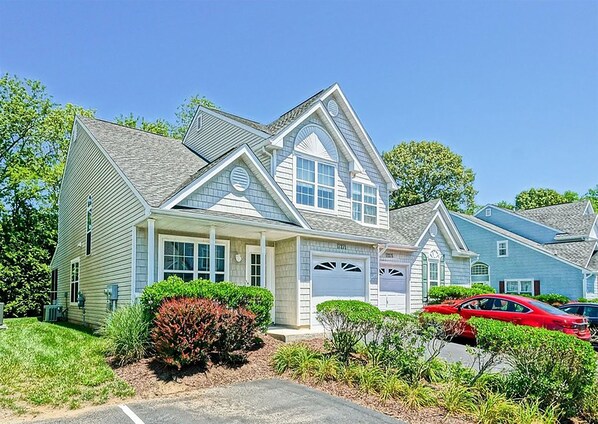 A single-story house with a gabled roof, a front garage, and a well-maintained front yard with shrubs and a lawn.
