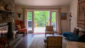 Ein gemütliches Wohnzimmer mit Kamin, einem blauen Sofa und einer großen Schiebetür zu einem Außenbereich.