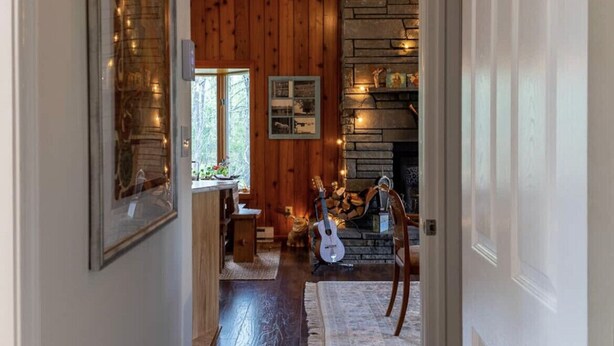 Ein gemütliches Interieur mit Holzwänden, einem Steinkamin und einer Gitarre.
