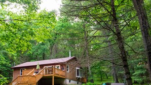 Eine Holzhütte mit einer Holzterrasse, einer Veranda und einer kleinen Sitzgelegenheit im Freien.