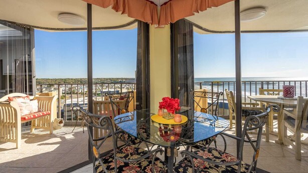 A balcony with a glass table, chairs, and a view of the ocean. - Elegant Oceanfront 2 Bedroom 2 Bath Ocean View Condo at Maisons-Sur-Mer in Myrtle Beach (Myrtle Beach)