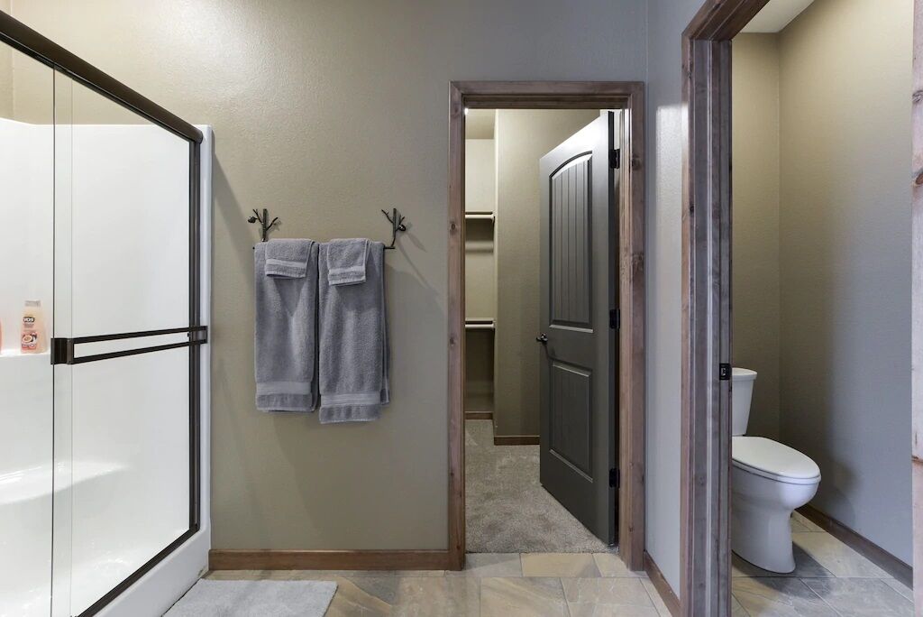 Ein Flur mit einem weißen Kühlschrank, einem Handtuchhalter mit zwei Handtüchern, einer Holztür und einer Toilette.