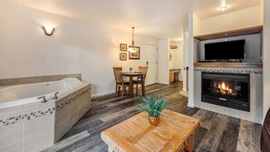 A modern living room with a fireplace, a dining area, and a large bathtub. - Fall River Escape; Perfect Getaway on Fall River! (Estes Park)