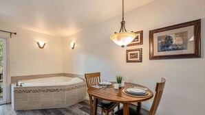 A bathroom with a bathtub, a wooden dining table with chairs, and wall-mounted light fixtures. - Fall River Escape; Perfect Getaway on Fall River! (Estes Park)