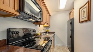 A kitchen with wooden cabinets, a stainless steel stove, a microwave, and a refrigerator. - Fall River Escape; Perfect Getaway on Fall River! (Estes Park)