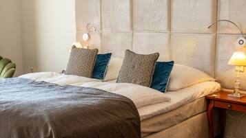 A hotel room with a large bed, two bedside lamps, a nightstand, and a green chair.