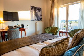 A hotel room with a bed, a desk with a computer, a television, a chair, and a view of the outdoors. - Hotelzimmer - Van der Valk Resort Linstow Hotel (Dobbin-Linstow)