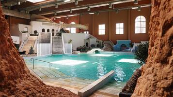 An indoor swimming pool with a slide, stairs, and a Buddha statue.