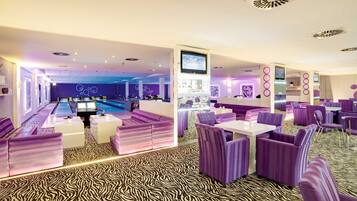 A modern lounge area with purple seating, a pool table, and a bar.