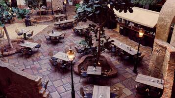 An indoor courtyard with multiple tables and chairs, surrounded by brick walls and stone flooring.