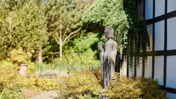 A statue in a garden with a pathway and greenery.