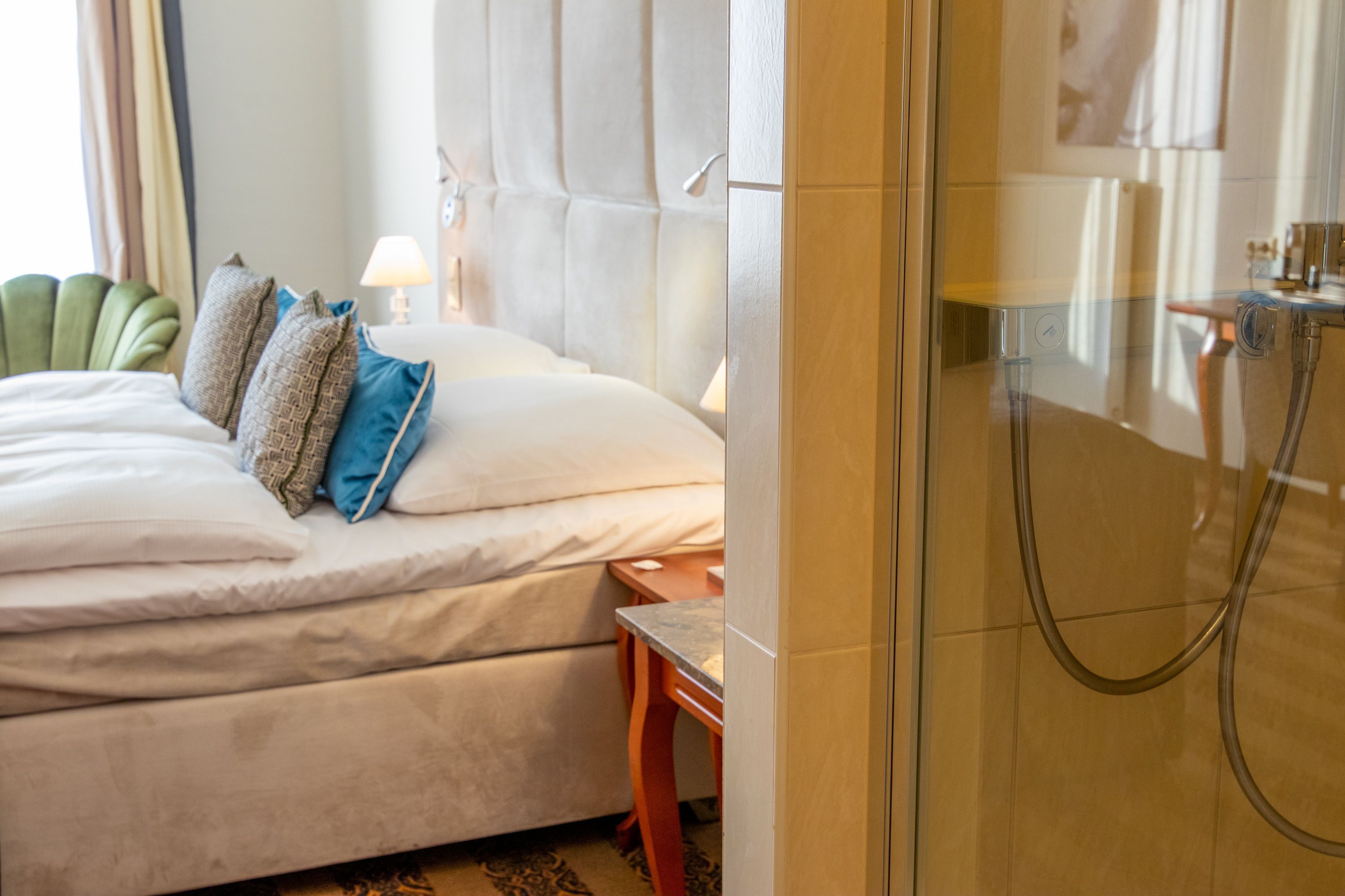 A hotel room with a bed, a nightstand, a lamp, and a shower area.