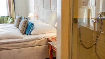 A hotel room with a bed, a nightstand, a lamp, and a shower area.