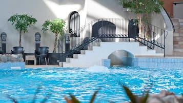 A swimming pool with a staircase leading to a covered area, surrounded by potted plants and stone features.