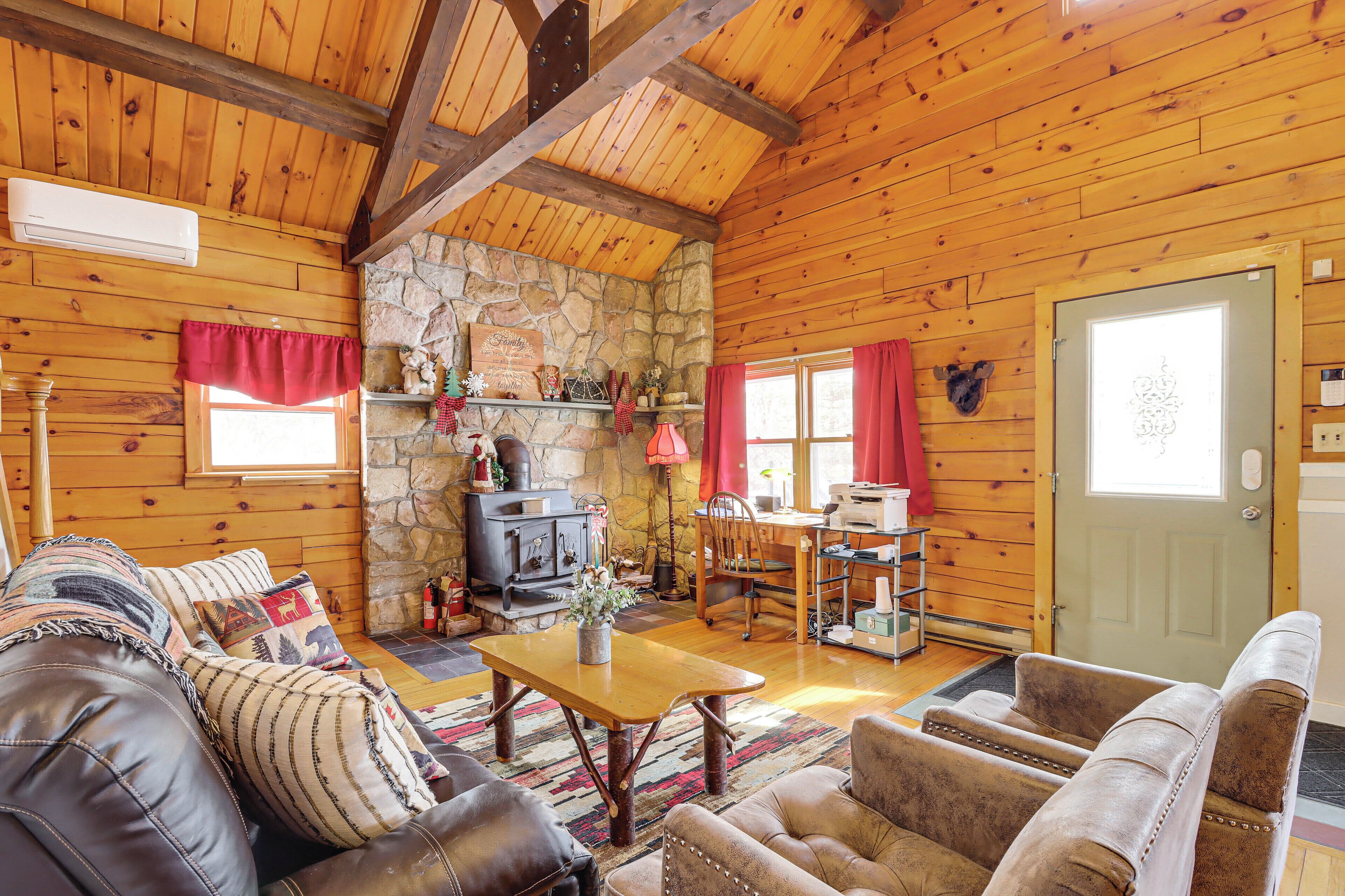 Een gezellig cabin interieur met een stenen open haard, houten wanden, lederen meubels en een eethoek.