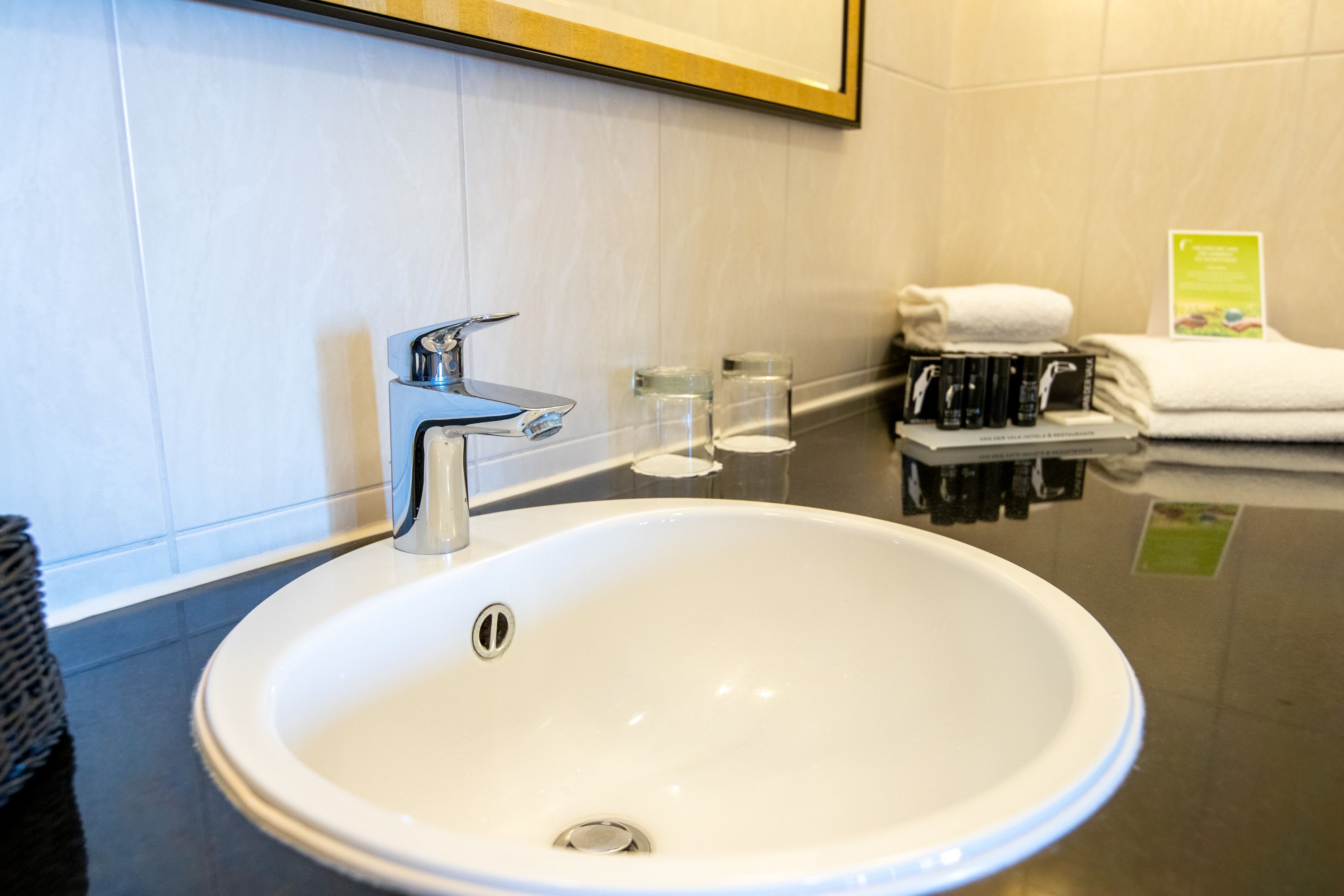 A white bathroom sink with a chrome faucet, a mirror above it, and a towel rack with folded towels.