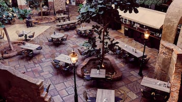 An indoor courtyard with multiple tables and chairs, surrounded by brick walls and stone flooring.