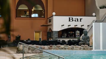 An indoor bar area with a pool, stone wall, and Buddha statue.