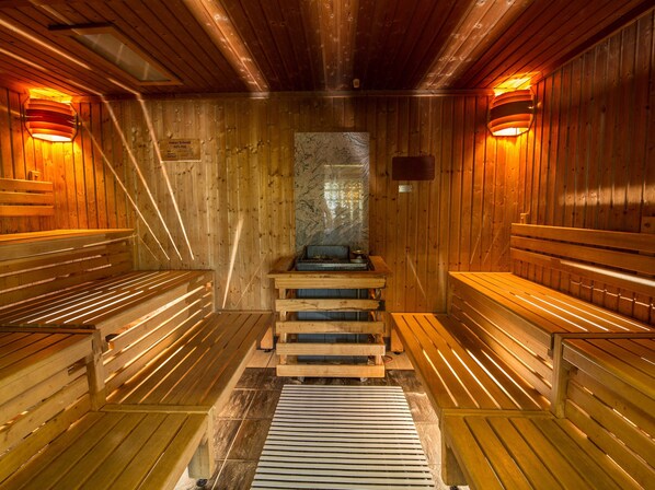 A sauna with wooden benches and benches, a stone wall, and wooden walls.