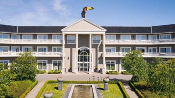 A multi-story building with a central entrance, a fountain, and a well-maintained garden.