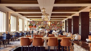 A spacious restaurant with high ceilings, modern bar seating, and a central dining area with a long table. - Hotel room (a) - Van der Valk Resort Linstow Hotel (Dobbin-Linstow)