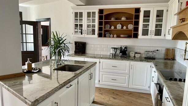 Une cuisine moderne avec des meubles blancs, un plan de travail en granit et un plancher en bois.