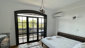 Une chambre à coucher comprenant un lit, une commode, une fenêtre donnant sur un paysage agréable et un appareil de climatisation.