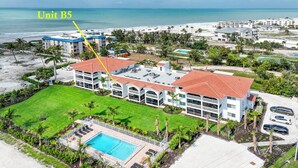 Een groot resort met een zwembad, meerdere gebouwen en uitzicht op het strand.