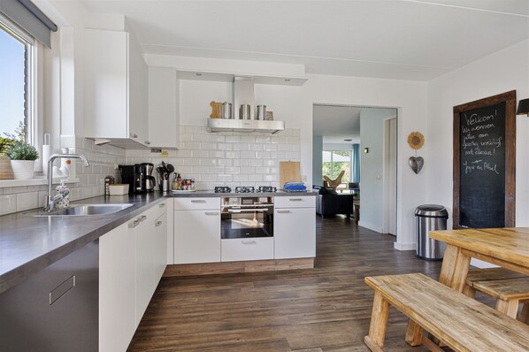 A modern kitchen with white cabinets, a stainless steel range hood, and a built-in oven.