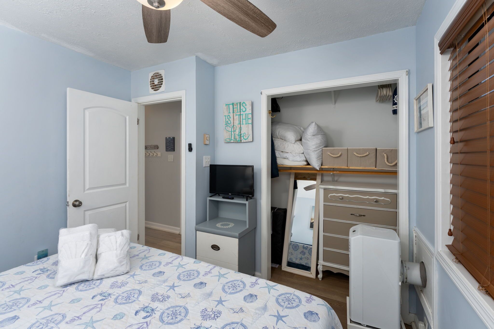 A bedroom with a bed, a TV, a closet, and a ceiling fan.