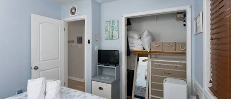 A bedroom with a bed, a TV, a closet, and a ceiling fan.