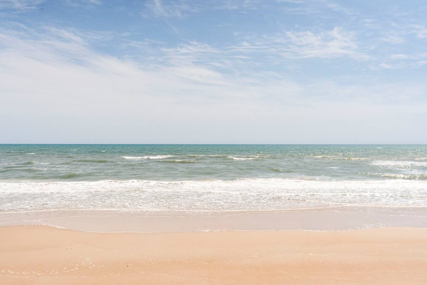 A beach with clear skies and calm waves.