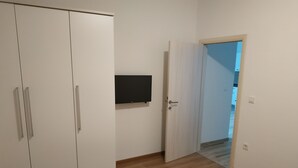 Una habitació amb un armari, una porta i un televisor de pantalla plana fixat a la paret.
