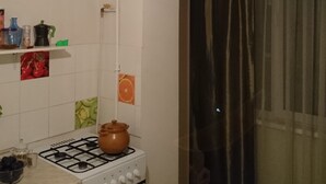 Cucina con piano cottura a gas, forno e lavatrice. Sopra il bancone, una lampada a sospensione.