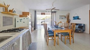 Eine Küche mit Gasherd, Holzschränken und einem Essbereich mit Tisch und Stühlen.