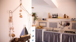 Eine Küche mit einem Holzregal, das Weinflaschen, einen Blumentopf und Dekorationsobjekte beherbergt.