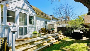 A white house with a front porch, steps leading to the entrance, and a small garden area with potted plants. - Classic Beach Cottage In Town (Rehoboth Beach)