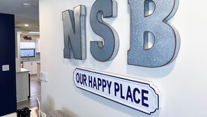 A wall with large letters spelling "NSB" and a sign below that reads "OUR HAPPY PLACE".