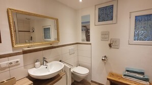 Ein Badezimmer mit großem Spiegel, Waschbecken, Toilette und einer kleinen Holzbank mit Handtüchern.