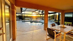 An outdoor patio with a pool, seating area, and a view of the sunset. - Disney Area Superior Deluxe With Gameroom (Davenport)