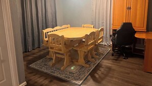 Ein Essbereich mit Holztisch und -stühlen, einem Deckenventilator und einer Küchenzeile mit Holzausstattung.