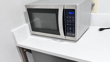 Un horno microondas sobre una encimera blanca con el logotipo de Hisense, un enchufe y un cable en la pared.
