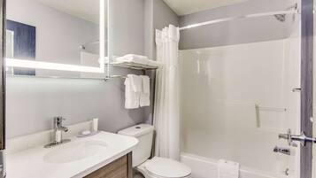 A modern bathroom with a white sink, toilet, and bathtub. There is a shower curtain, a towel rack, and a mirror above the sink.