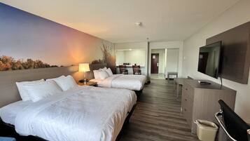 Een hotelkamer met twee bedden, een bureau, een stoel, een televisie en een badkamer in de achtergrond.
