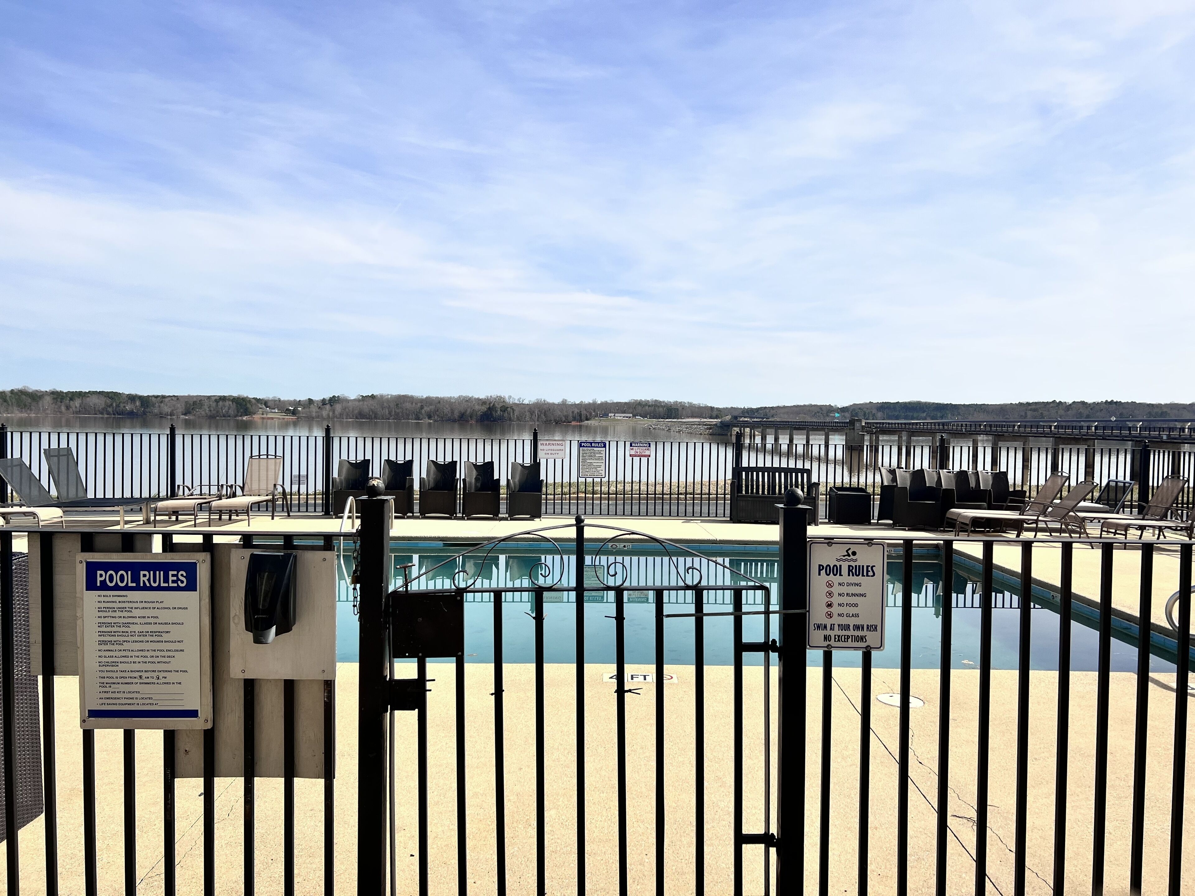 A pool area with lounge chairs and a sign detailing pool rules.
