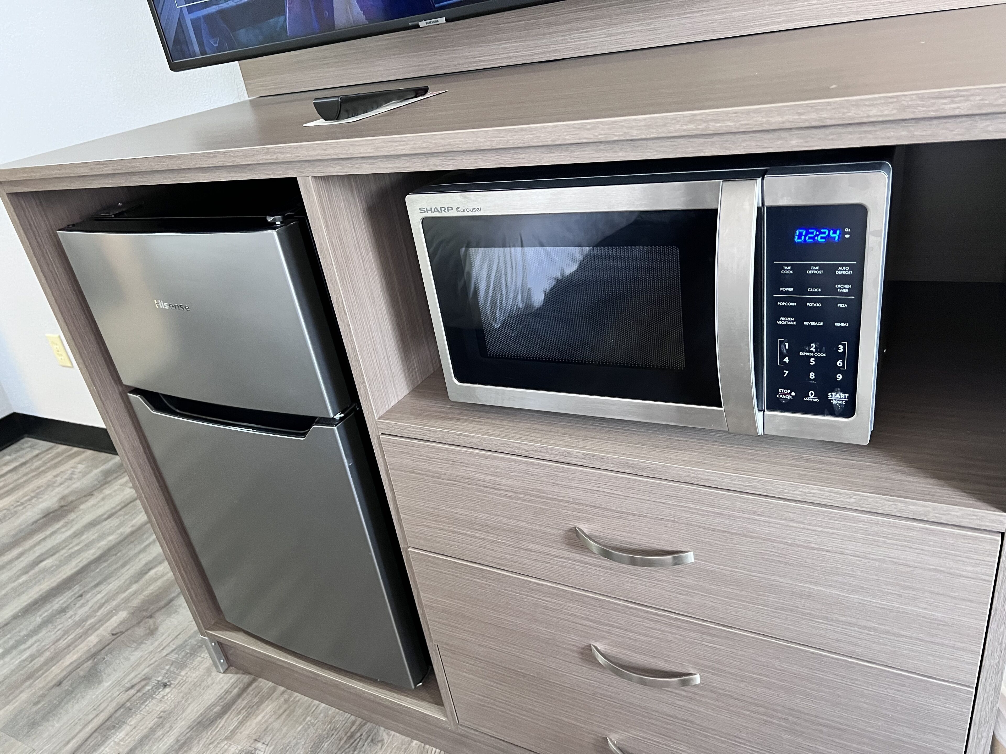 A kitchen with a stainless steel refrigerator and a microwave with a digital display.