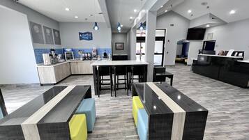 Un área de recepción moderna con mostrador, asientos y una estación de café.
