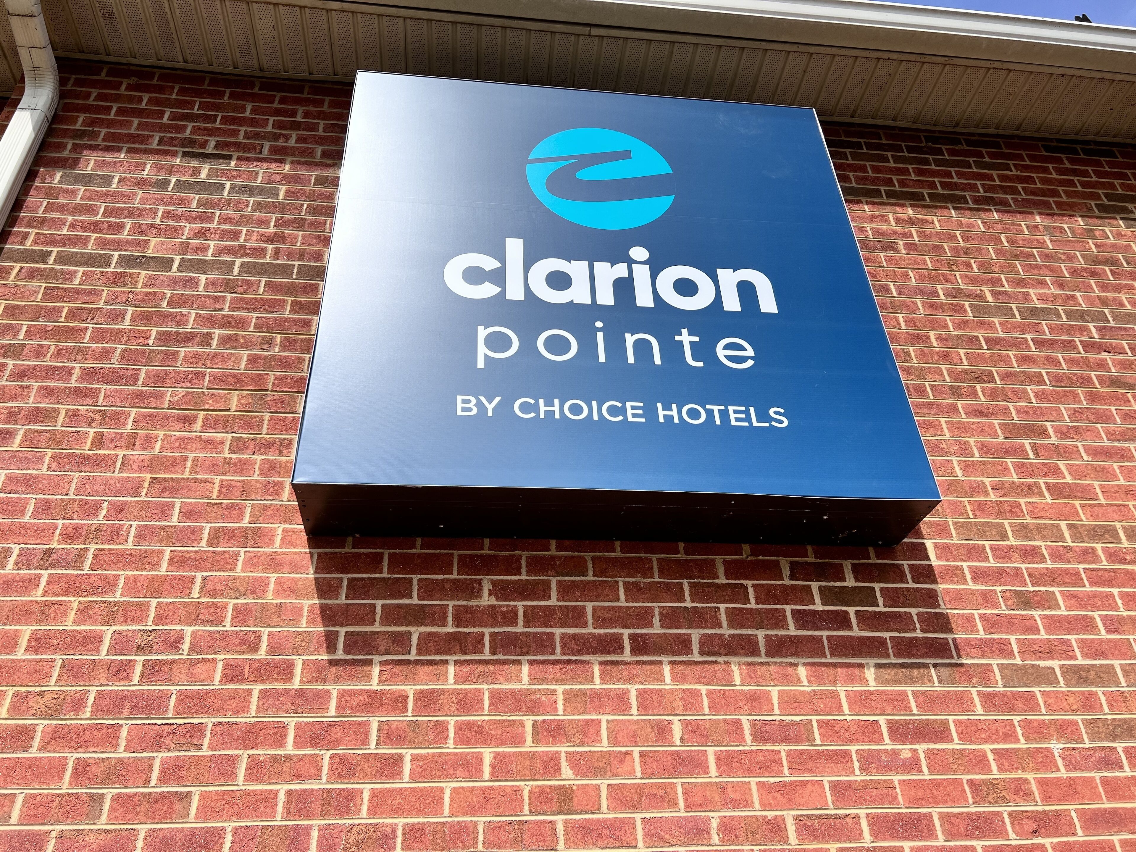 A blue sign with the text "Clarion Pointe by Choice Hotels" on a brick wall.